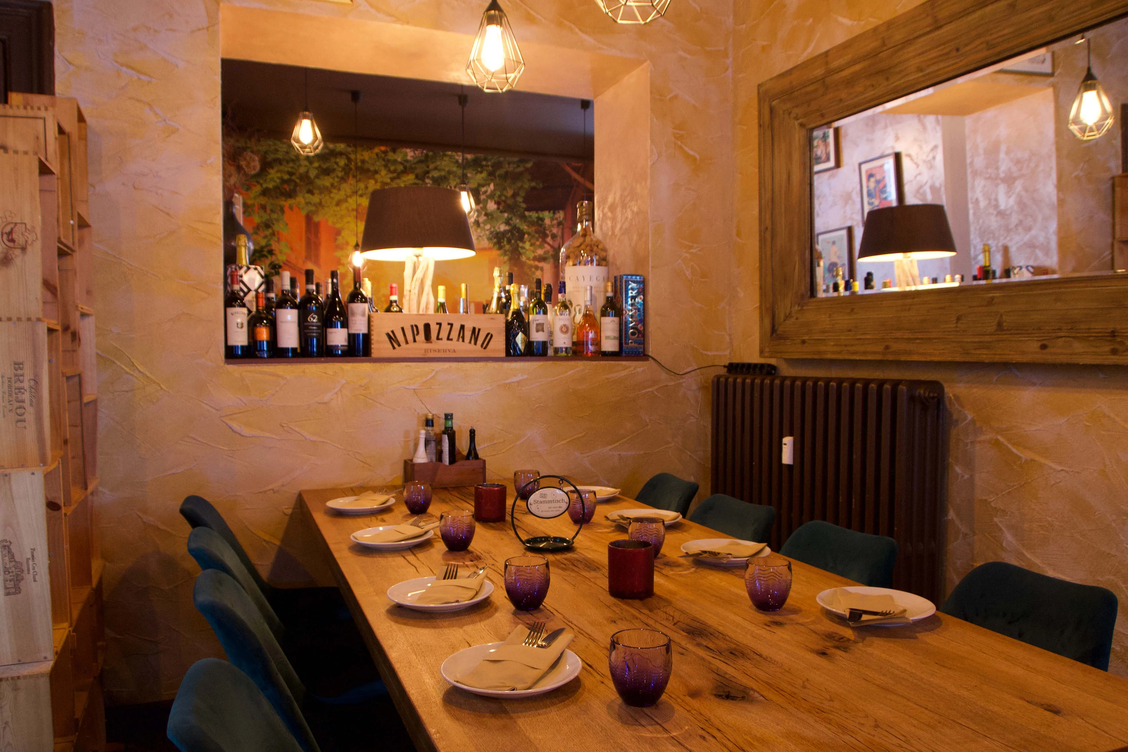 Das Weinregal mit italienischen Flaschen über dem langen Holztisch