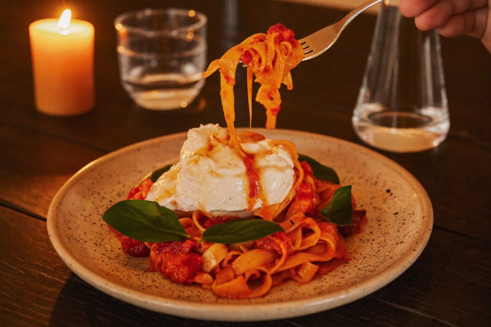 Tagliatelle mit Burrata und San-Marzano-Sugo auf dunklem Holztisch